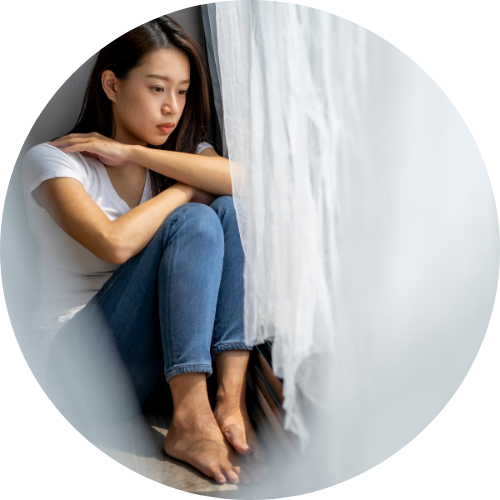 カーテンの裏でうずくまっている女性