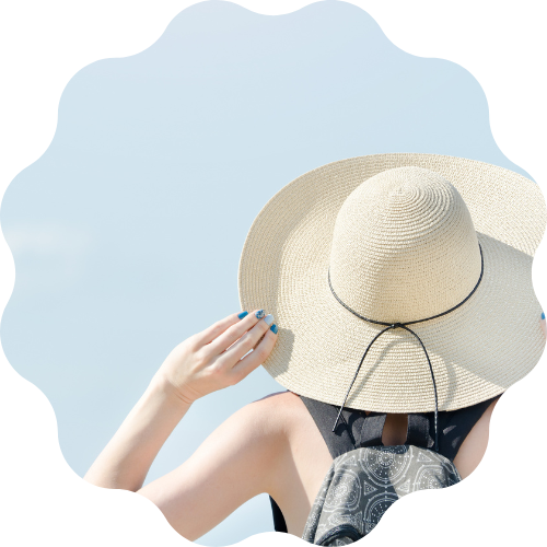 かぶっている麦わら帽子に手を当てている後ろ向きの女性