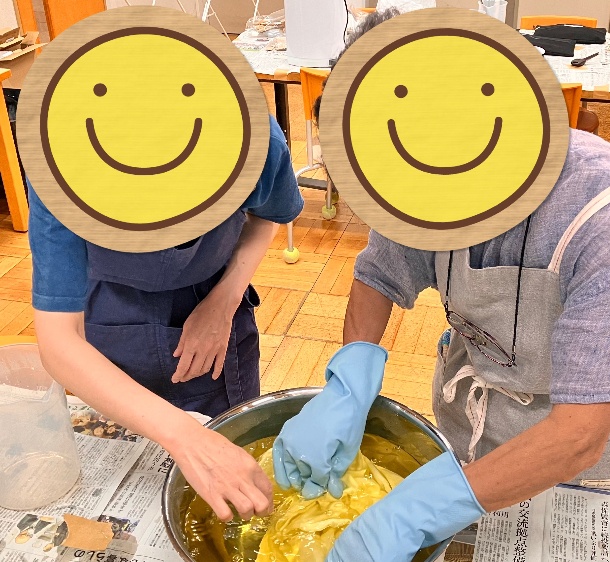 草木染めワークショップでレモングラス染めをしている写真。ボウルのレモングラスの染液でストールを染めています。