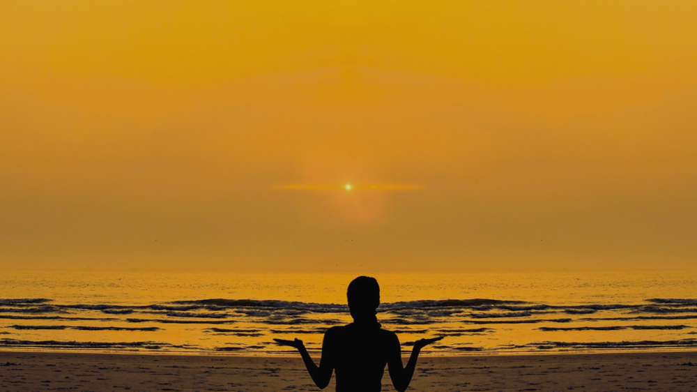 夕日が照らすビーチにいいる後ろ姿