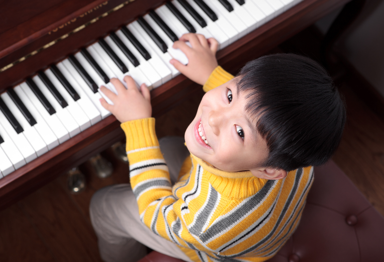 みずほピアノ教室の、無料体験レッスンとお問い合わせページ。子供がピアノ教室のグランドピアノを弾いてる画像。