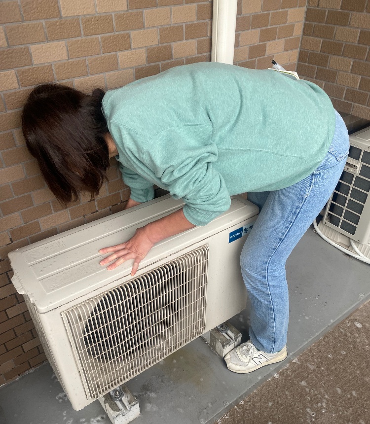 室外機の清掃をする女性