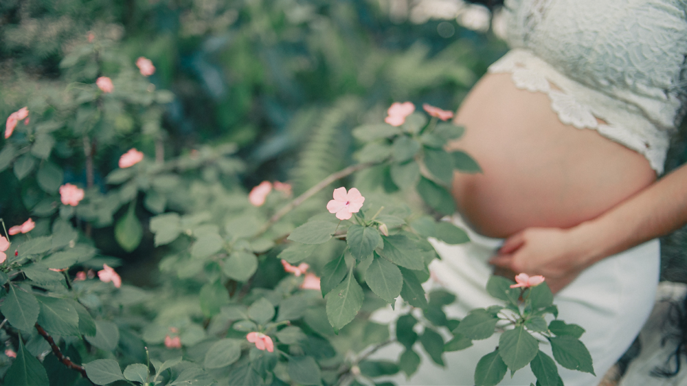 緑の葉とピンクの小花とマタニティ姿